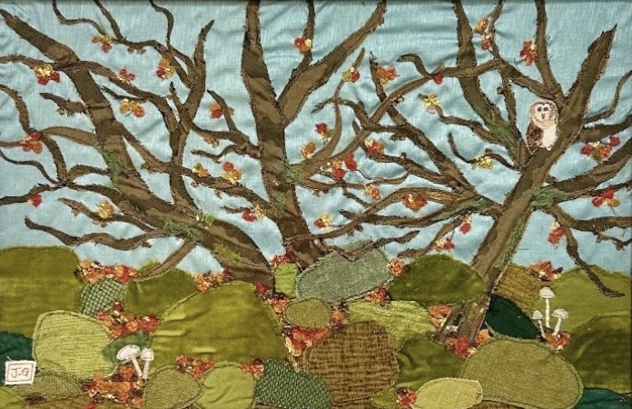 Textile art of a woodland with boulders and an owl, by Jackie Gale, available through Wildwood Art Gallery